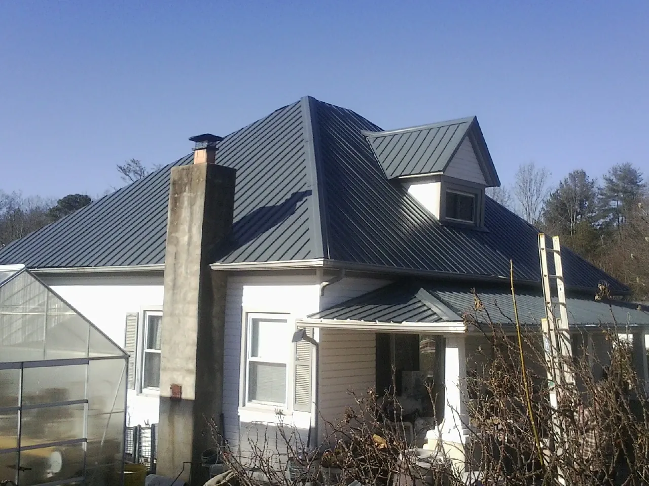 Dark blue standing seam metal roof on a white farmhouse with dormer — Slate & Tile Roof Repair by Roofing Brothers in West Harwich