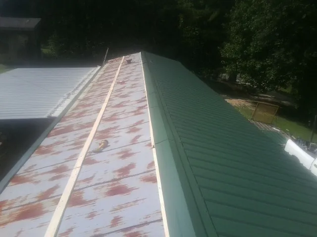 Old rusted panels beside newly installed green metal roofing — Wind Damage Roof Repair by Roofing Brothers in West Harwich