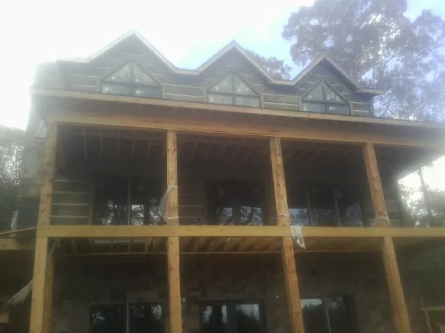 Dormers and porch framing on a large log home under construction — Roof Coating work by our crew in West Harwich