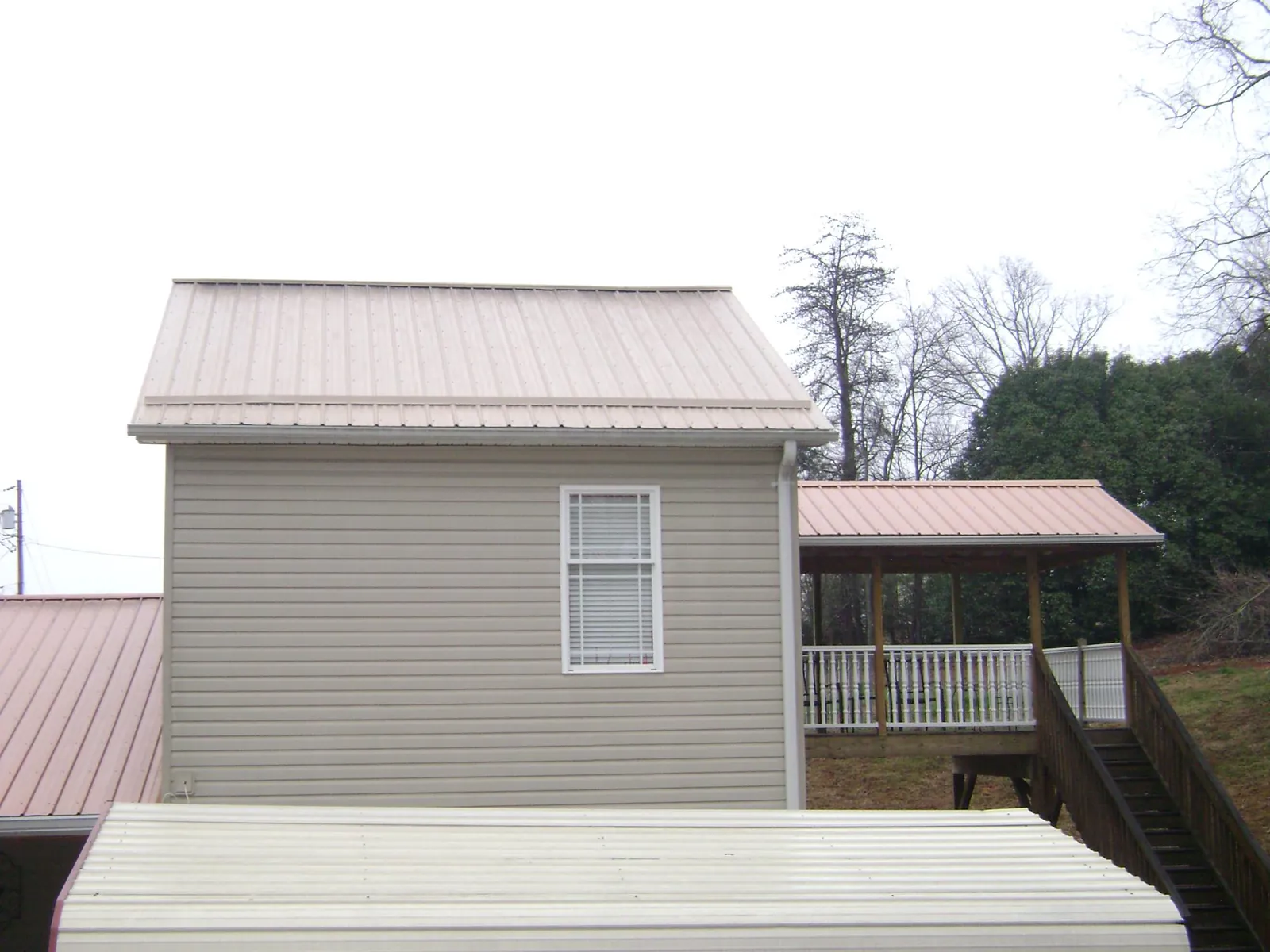 Tan metal roofs on a two story addition and attached porch, from a Roof Replacement job in West Harwich