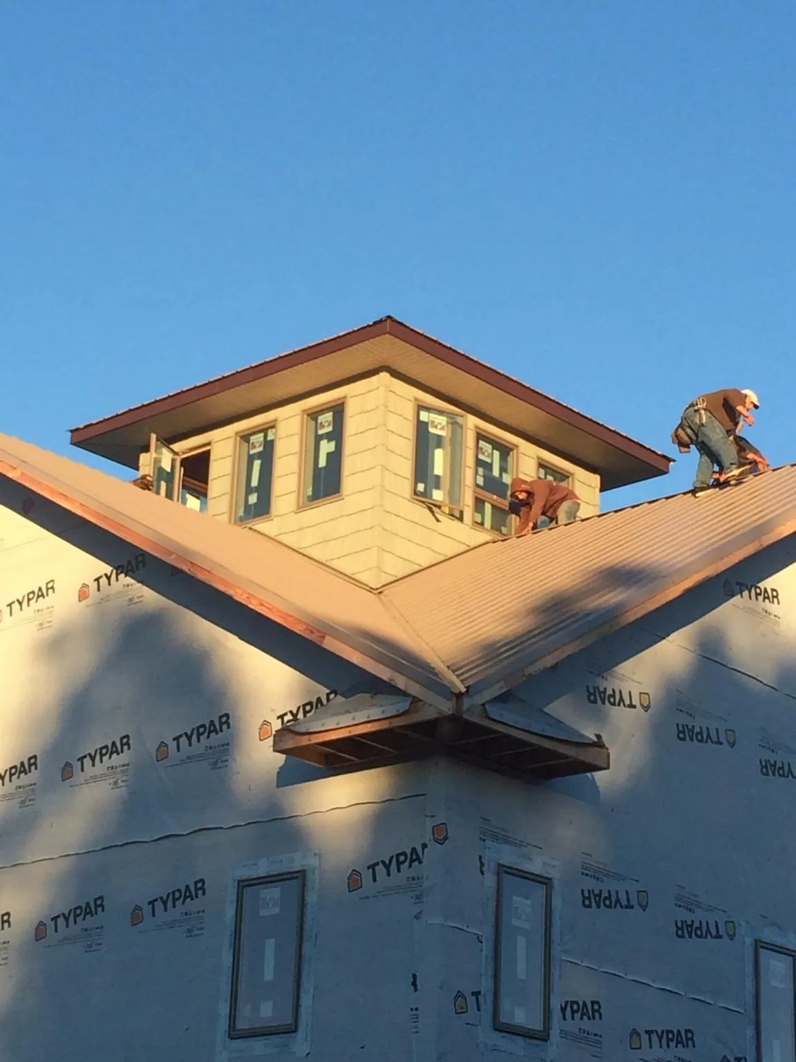 Roofers working around a rooftop cupola on a new metal roof at sunset — Roof Waterproofing in West Harwich by Roofing Brothers
